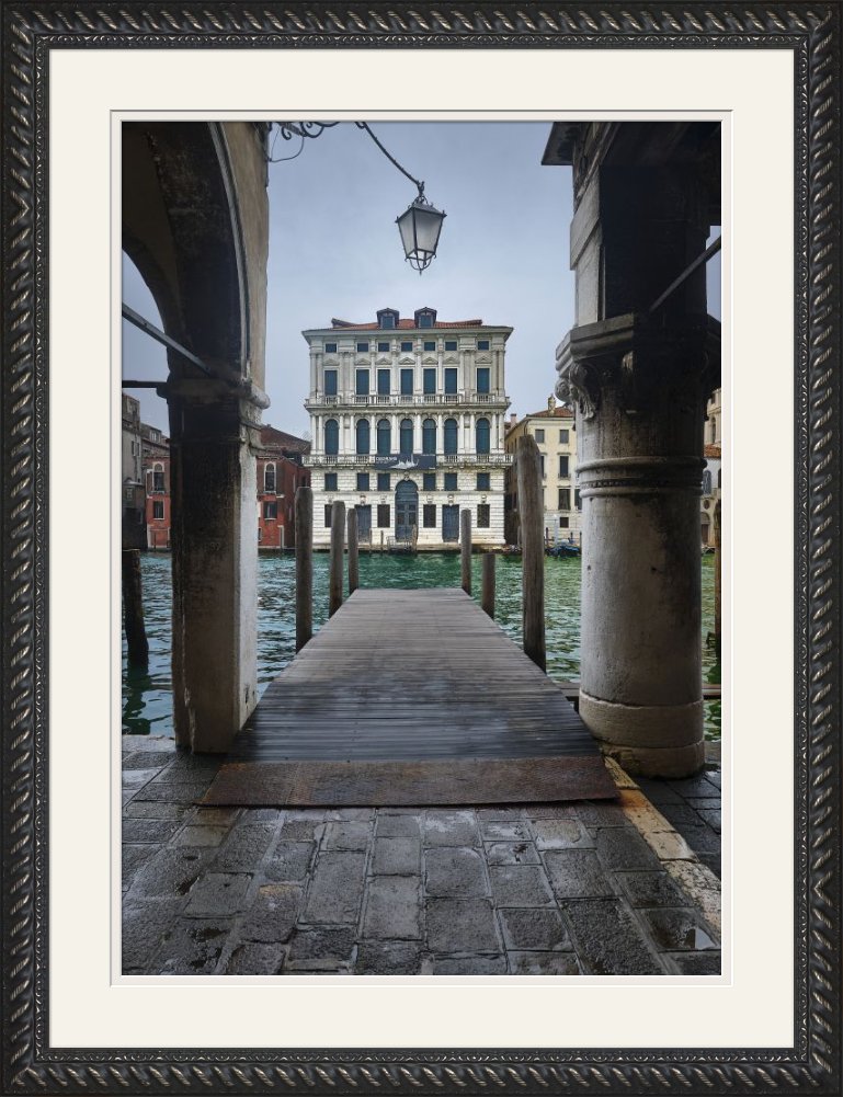 Framed photograph of a Venice canal seen through a stone arcade, in an ornate black frame