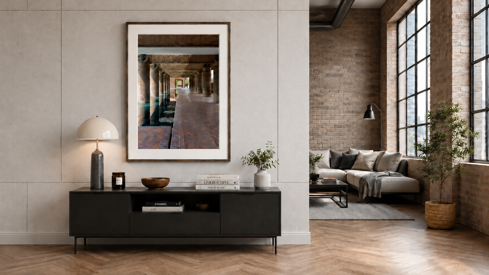 A museum grade framed print above a media console, opening onto an adjoining exposed brick loft
