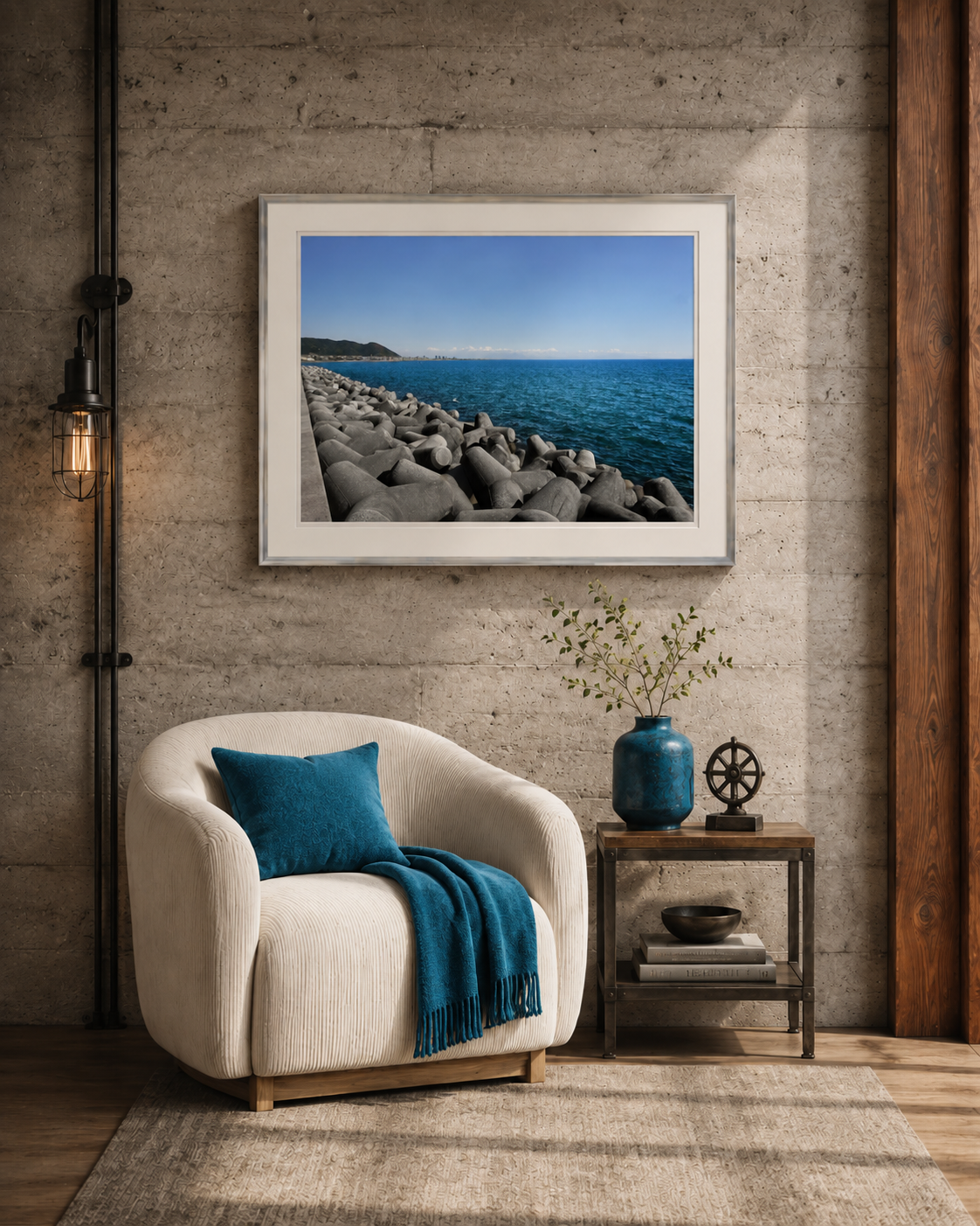 A museum grade framed seascape print hung above a cream armchair against an exposed concrete wall